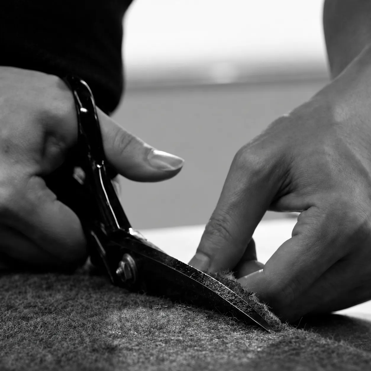 Garment fabric being cut by hand using industrial scissors